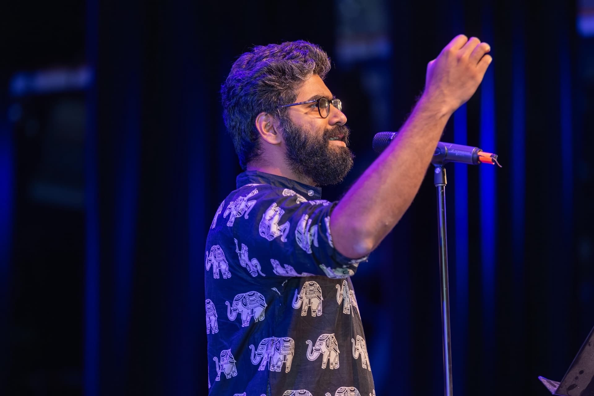 Aakash Binu performing on stage with microphone.