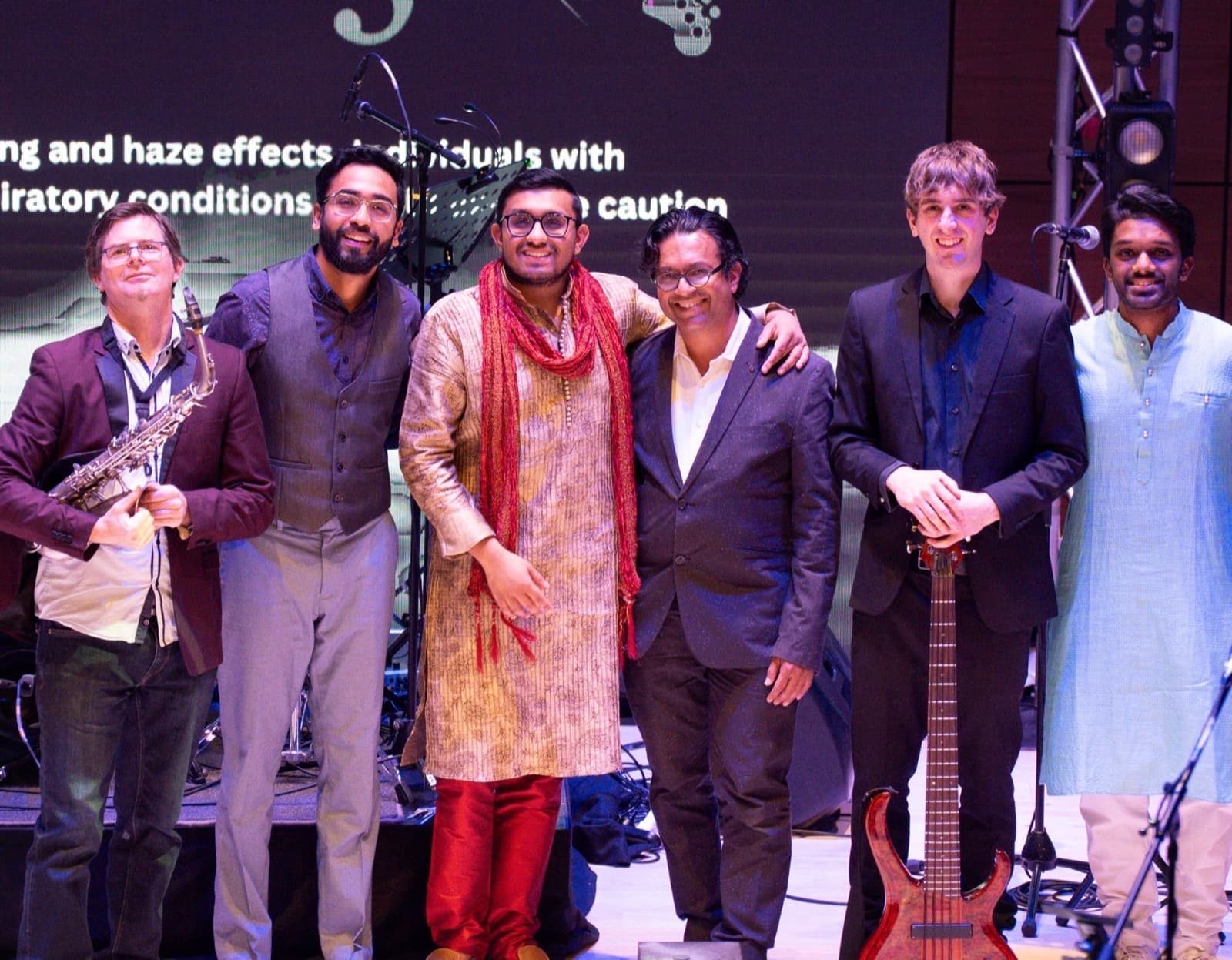 Arohana ensemble of six musicians on stage with saxophone and bass guitar.
